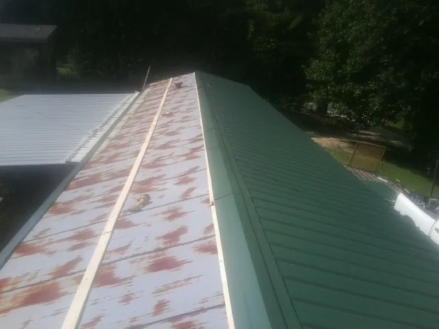 Old rusted panels beside newly installed green metal roofing — Wind Damage Roof Repair by Roofing Brothers in Orchard Park