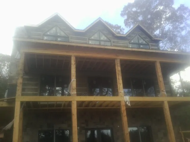 Dormers and porch framing on a large log home under construction — Roof Coating work by our crew in Orchard Park