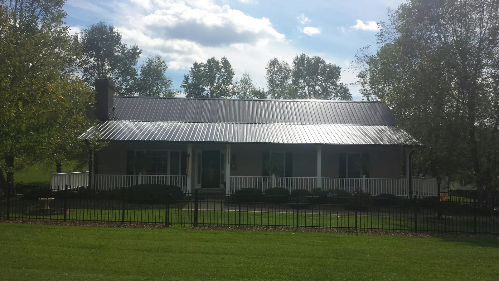 Gray metal roof on a brick ranch with a full width front porch — Gutter Guard Installation work by our crew in Orchard Park