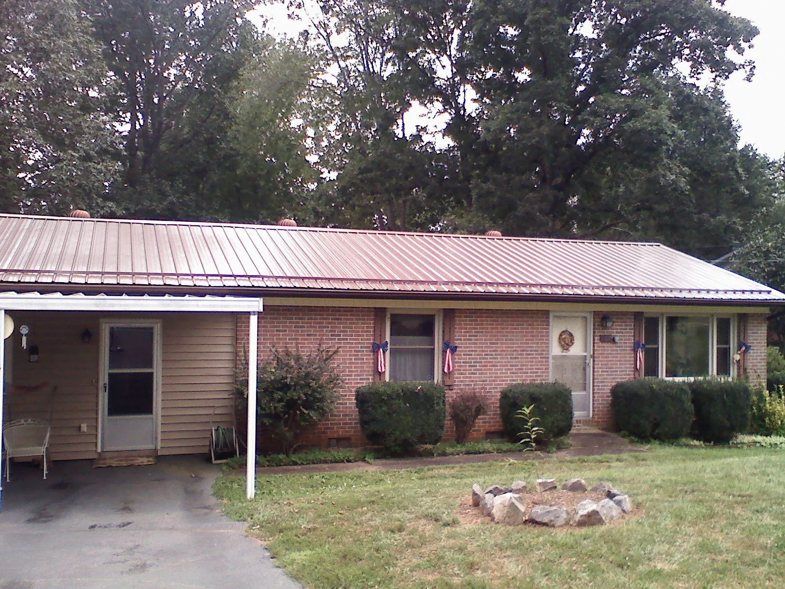 Bronze metal roof and carport on a brick ranch home — Roof Repair work by our crew in Orchard Park