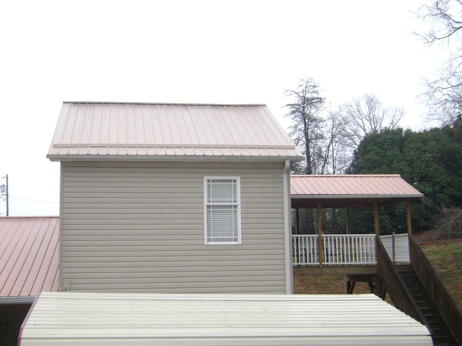 Tan metal roofs on a two story addition and attached porch, from a Roof Replacement job in Orchard Park