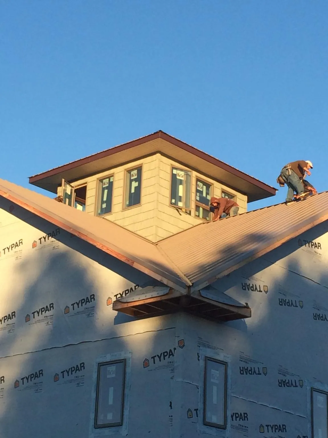 Roofers working around a rooftop cupola on a new metal roof at sunset — Roof Waterproofing in Orchard Park by Roofing Brothers